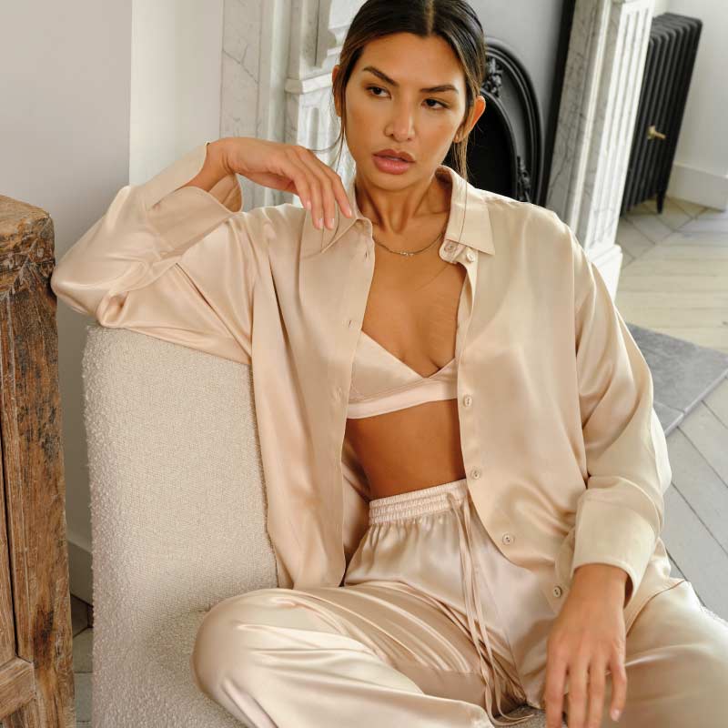 Model wears luxury blush silk shirt and trouser pyjama set by Fleur of England